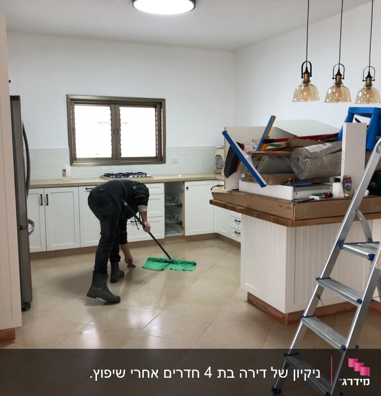 אדם מנקה רצפה עם מגב ירוק במטבח